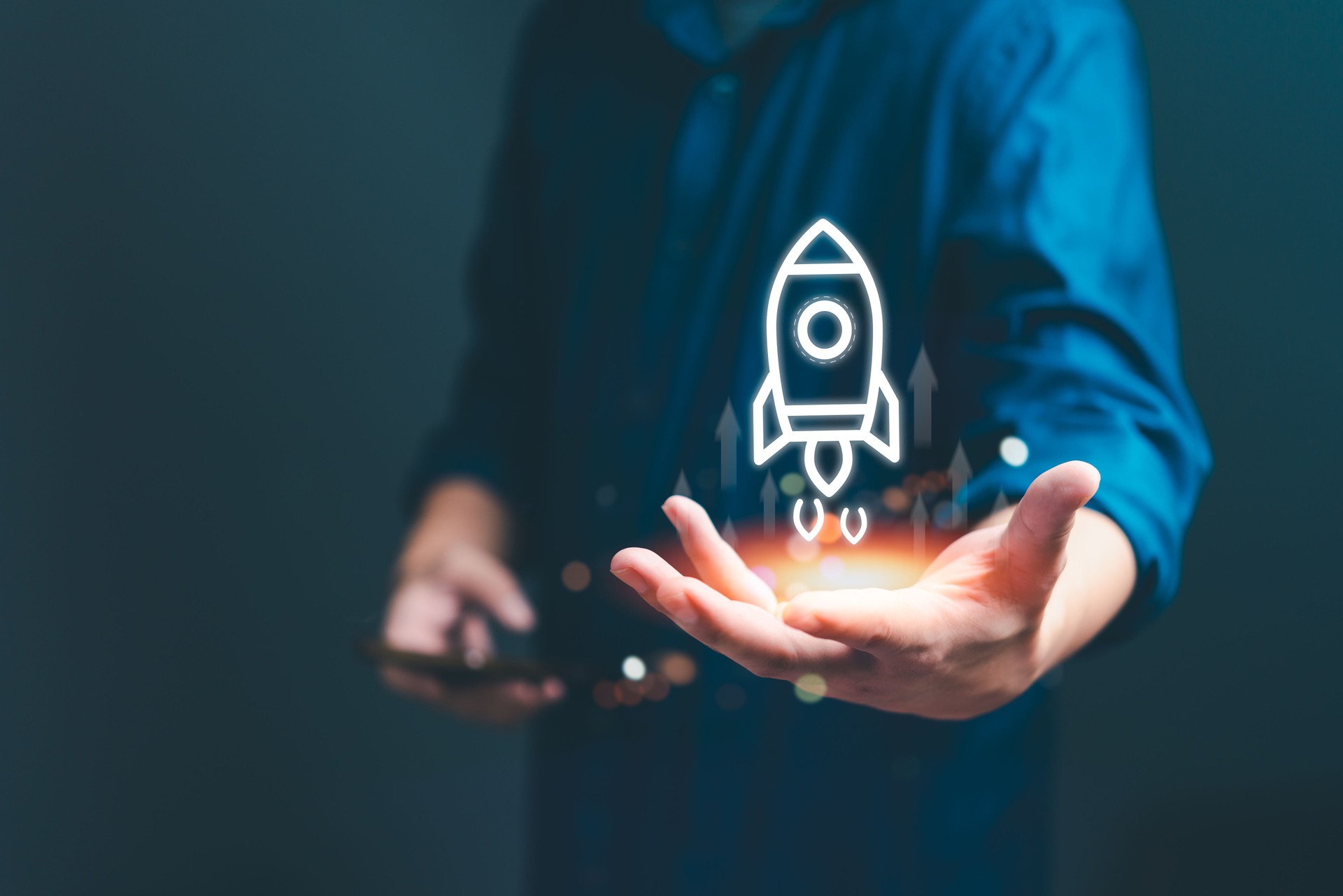 Hand holding digital hologram of a rocket launching. Symbolizes startup growth and innovation. Perfect for business development, entrepreneurship, and technology presentations.